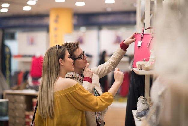 Duas amigas no shopping andam no shopping com sacolas e fazem escolhas