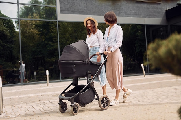 Foto duas amigas passeando com carrinho de bebê ao ar livre