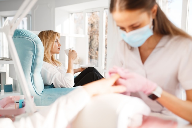 Duas amigas relaxam no procedimento de pedicure no salão de beleza. esteticista profissional e clientes do sexo feminino, tratamento de unhas em spa