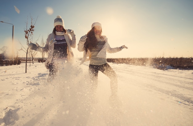 Duas amigas se divertem e aproveitam a neve fresca em um lindo dia de inverno