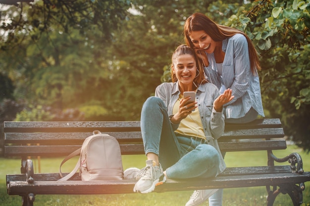 Duas amigas se divertem no parque ouvindo música no telefone