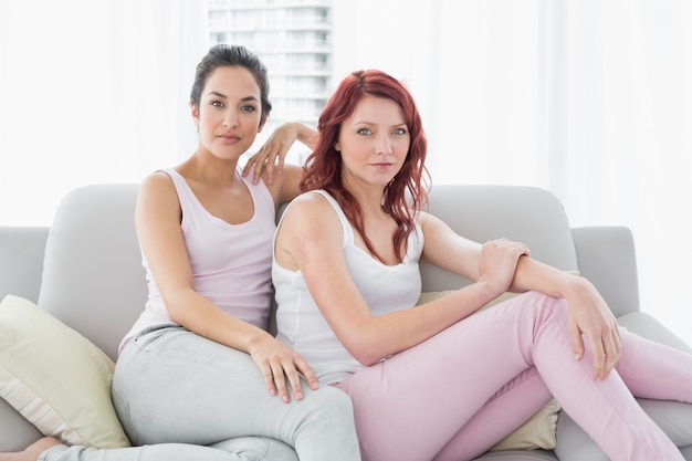 Duas amigas sérias e bonitas sentadas na sala de estar