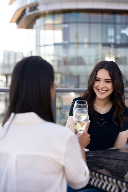 Duas amigas tomando um vinho juntas em um terraço na cobertura