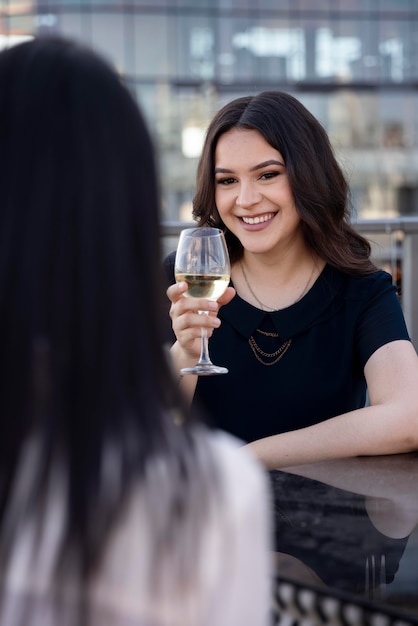 Duas amigas tomando um vinho juntas em um terraço na cobertura