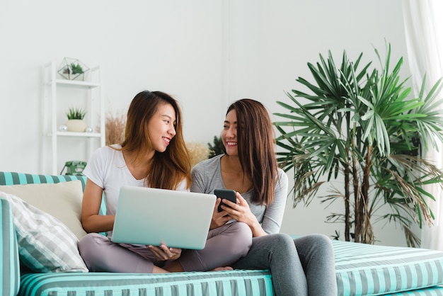 Duas amigas usam compras de cartões de crédito on-line com o computador laptop sentado no sofá em casa