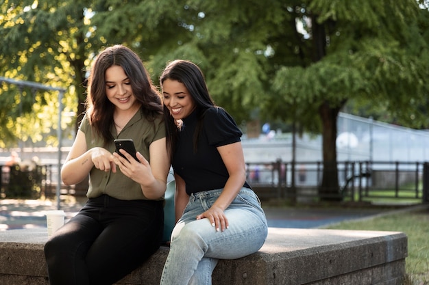 Foto duas amigas usando smartphone no parque