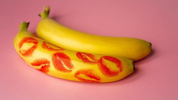 Duas bananas com vestígios de batom vermelho no fundo rosa, conceito de amor