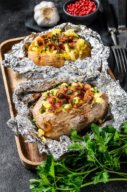 Duas batatas assadas com bacon, cebola verde e queijo.