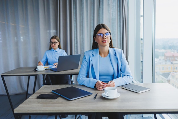 Duas belas jovens mulheres de negócios estão trabalhando e discutindo pontos de trabalho no escritório Namoradas em locais de trabalho no escritório Grande escritório moderno com janelas