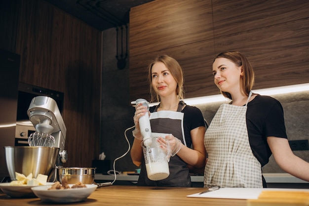 Duas belas mulheres em aventais preparam doces na cozinha