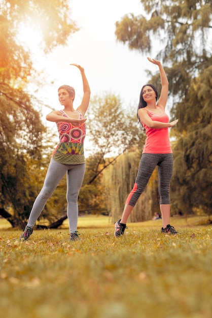 Duas belas mulheres fazendo ioga no parque.