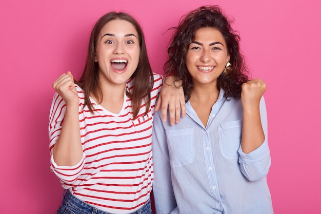 Duas belas mulheres felizes e entusiasticamente apertam os punhos. A alegria da vitória e da felicidade