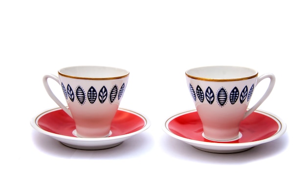Duas belas xícaras de café vermelhas com padrões de pires, isoladas em fundo branco
