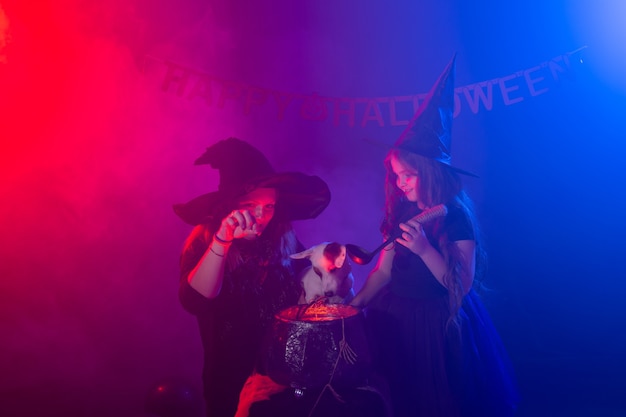 Duas bruxas de halloween fazendo mágica com dog jack russell terrier em feriados mágicos à noite de halloween