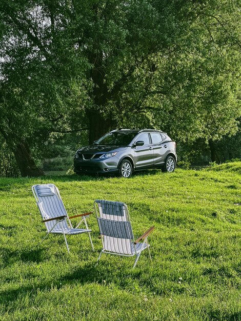 Foto duas cadeiras portáteis em campo verde suv carro no fundo