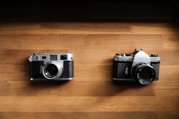 Duas câmeras de filme retrô estão sobre uma mesa de madeira