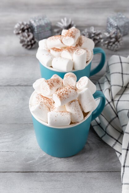 Duas canecas de chocolate quente servidas com marshmallow em um fundo cinza, copie o espaço