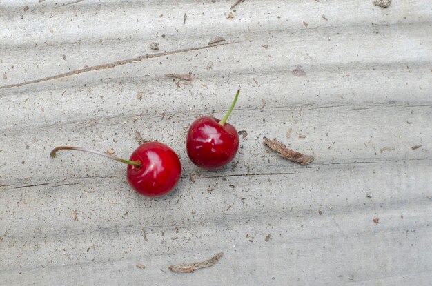 duas cerejas frescas na mesa de madeira ao ar livre