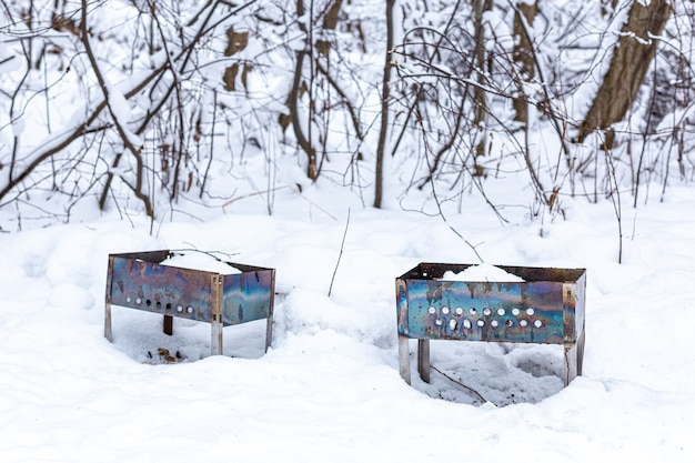 Duas churrasqueiras ou braseiros esquecidos na floresta de inverno na neve