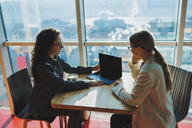 Duas colegas de trabalho e colegas discutindo o trabalho conjunto em um projeto de negócios usando uma executiva de laptop explicando uma nova ideia on-line para um colega de trabalho analisando a computação