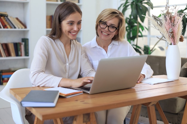 Duas colegas femininas trabalhando com laptop e discutindo um novo projeto.