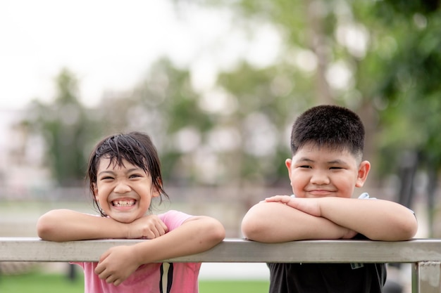 Duas crianças asiáticas, menino e menina, felizes e sorrindo no parque