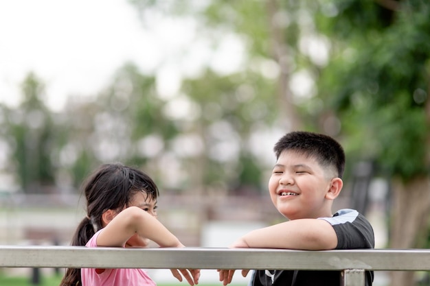 Duas crianças asiáticas, menino e menina, felizes e sorrindo no parque