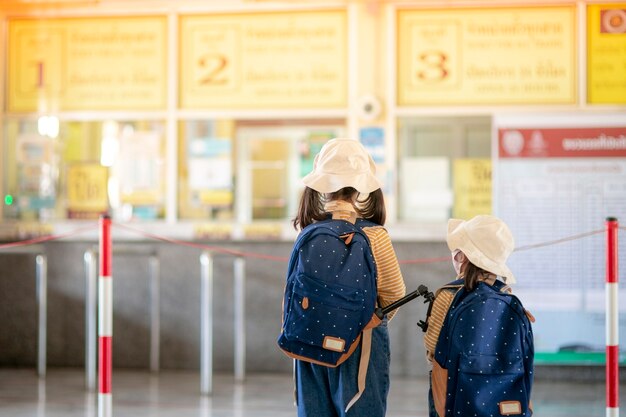 Duas crianças asiáticas na bilheteria da estação de trem