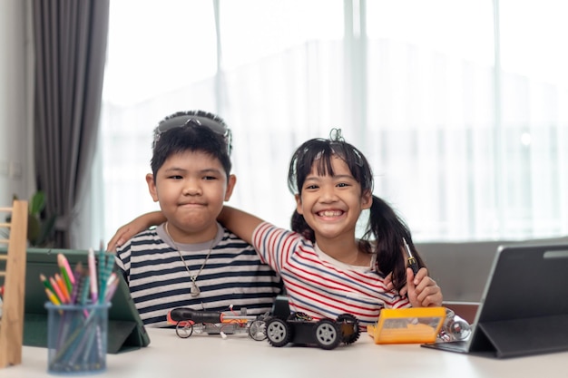 Duas crianças asiáticas se divertindo aprendendo a codificar juntos aprendendo remotamente em casa STEM science homeschooling educação diversão distanciamento social isolamento novo conceito normal