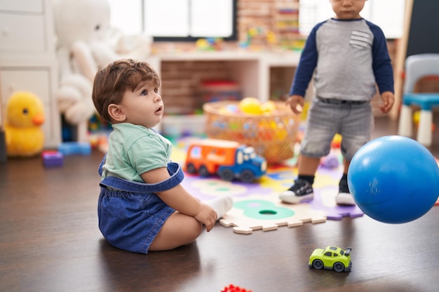 Duas crianças brincando com bola em pé no jardim de infância