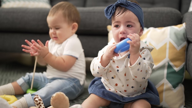 Duas crianças brincando com brinquedos sentados no chão em casa