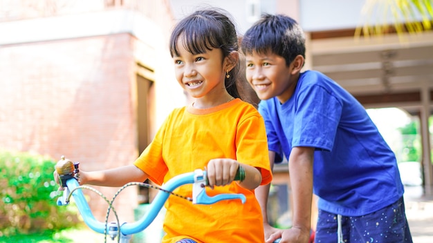 Duas crianças brincando de bicicleta no jardim atrás da casa