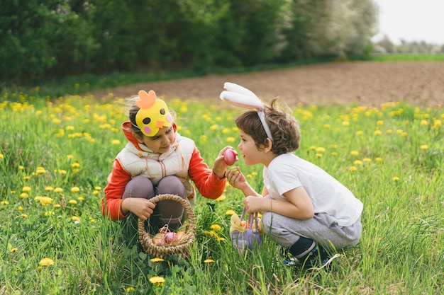 Duas crianças caçam ovos de Páscoa em um jardim de primavera Tradição da Páscoa