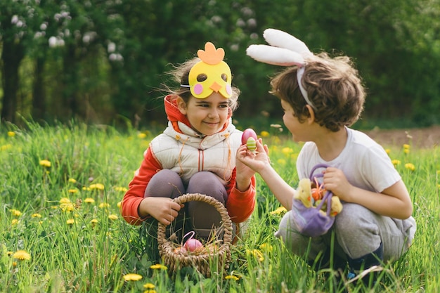 Duas crianças caçam ovos de Páscoa em um jardim de primavera Tradição da Páscoa