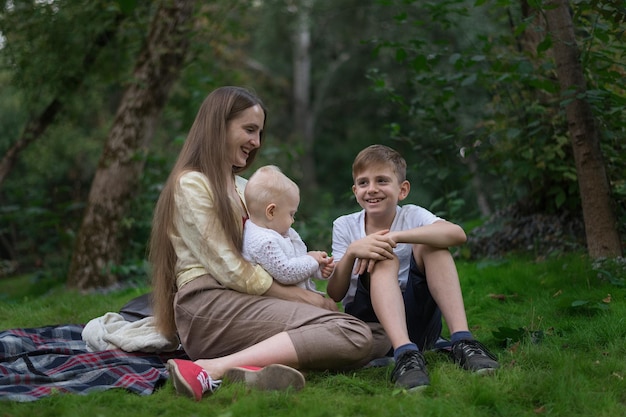 Duas crianças e uma mãe curtindo um piquenique no verão Família feliz descansando no parque