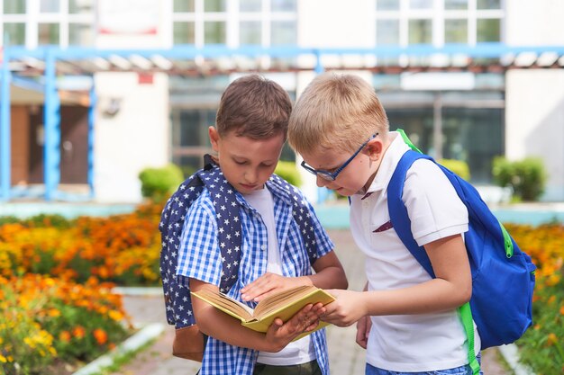 Duas crianças em idade escolar bonitos verificar seus trabalhos de casa no parque perto da escola.