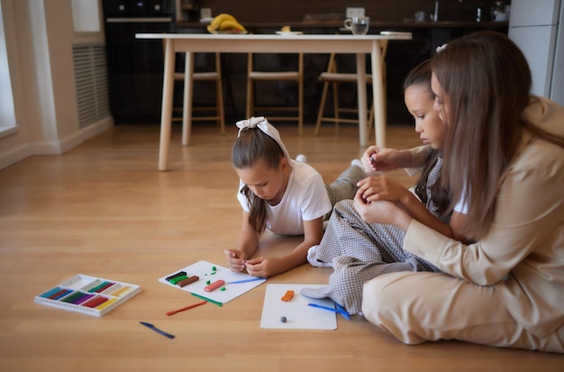 Duas crianças em idade pré-escolar brincando com plasticina colorida e se divertindo focam na garota à direita