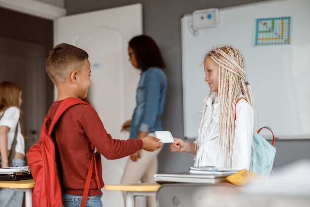 Duas crianças felizes com mochilas em pé na classe