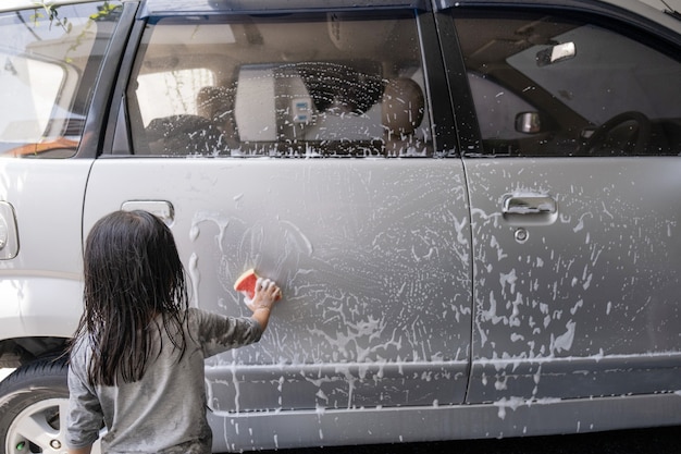 Duas crianças felizes lavando o carro do papai em casa