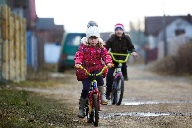 Duas crianças felizes menino e menina, andar de bicicleta ao ar livre em tempo frio