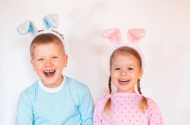 duas crianças felizes sorridentes com orelhas de coelhinho da Páscoa olhando para a câmera no fundo branco, copie o espaço