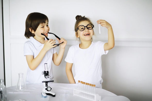 Duas crianças fofas na aula de química fazendo experimentos em fundo branco