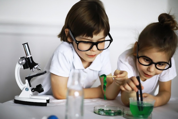 Duas crianças fofas na aula de química fazendo experimentos em fundo branco