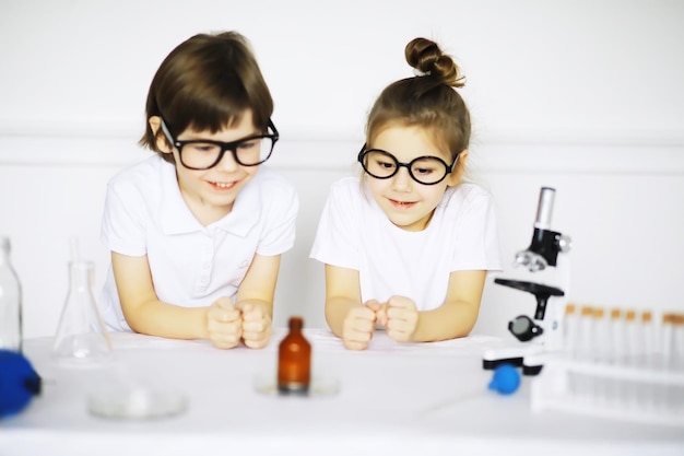 Duas crianças fofas na aula de química fazendo experimentos em fundo branco