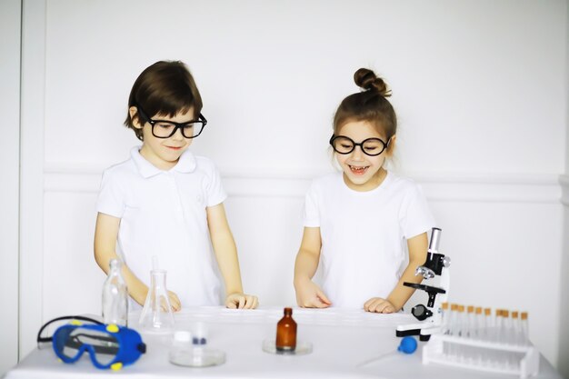 Duas crianças fofas na aula de química fazendo experimentos isolados no fundo branco