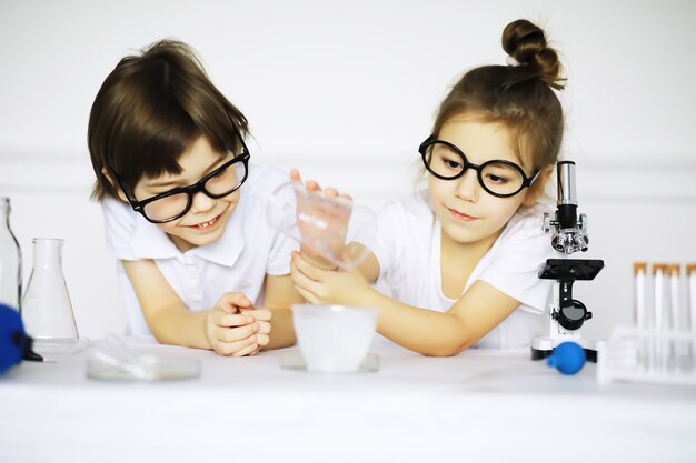 Duas crianças fofas na aula de química fazendo experimentos isolados no fundo branco