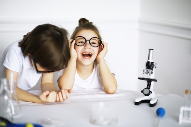 Duas crianças fofas na aula de química fazendo experimentos isolados no fundo branco