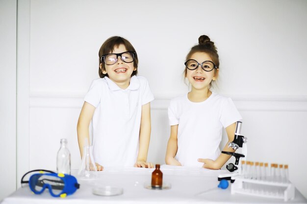 Duas crianças fofas na aula de química fazendo experimentos isolados no fundo branco