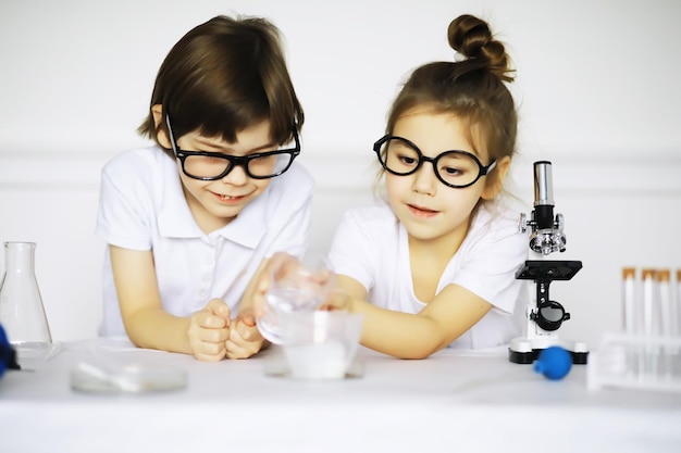Duas crianças fofas na aula de química fazendo experimentos isolados no fundo branco