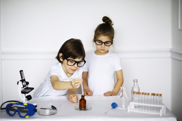 Duas crianças fofas na aula de química fazendo experimentos isolados no fundo branco